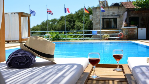 A poolside setting with a hat, towels, and a tray with glasses of wine. - Elianthos Villa (Apokoronas)