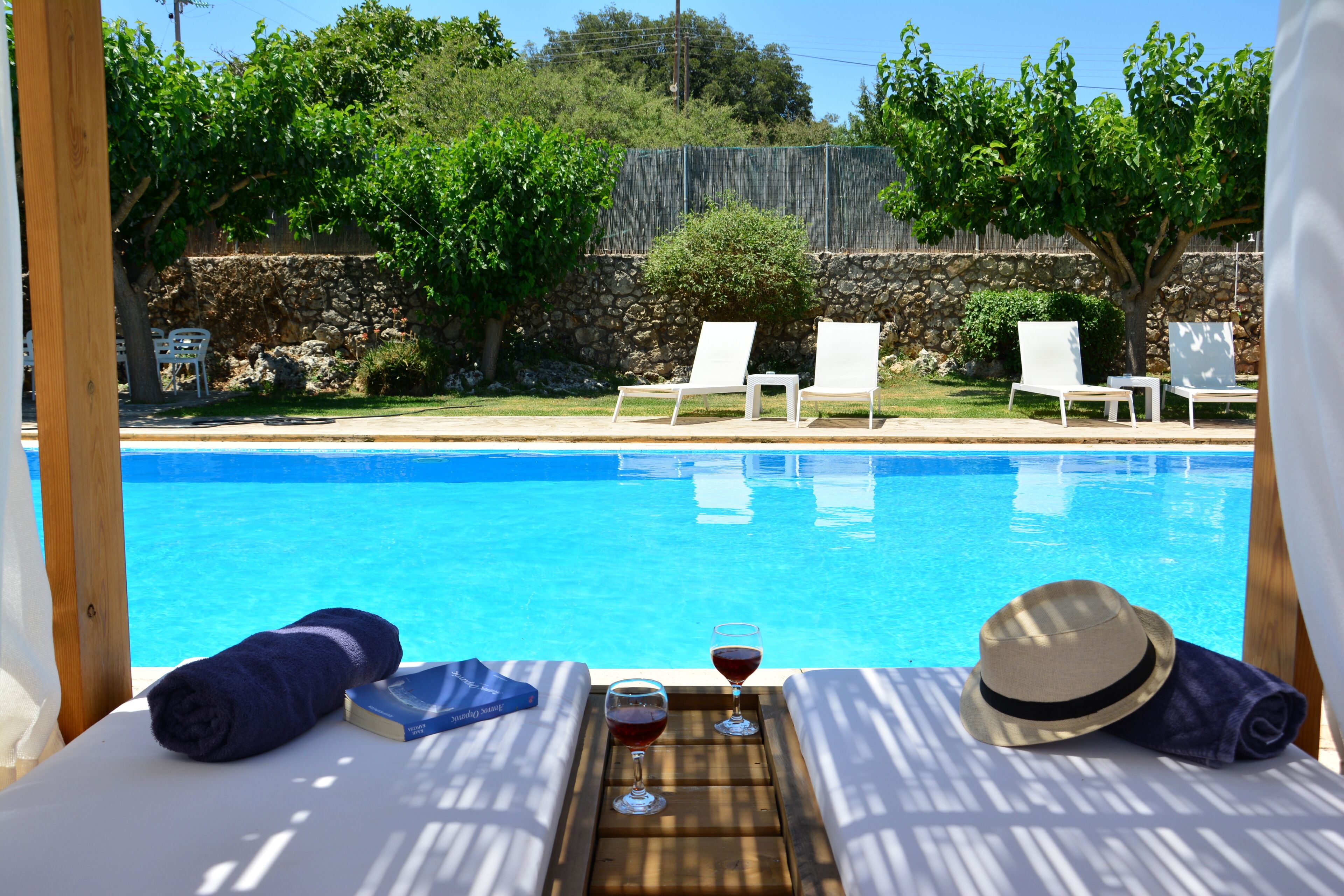 Una piscina al aire libre, sombrillas, sillones reclinables de piscina