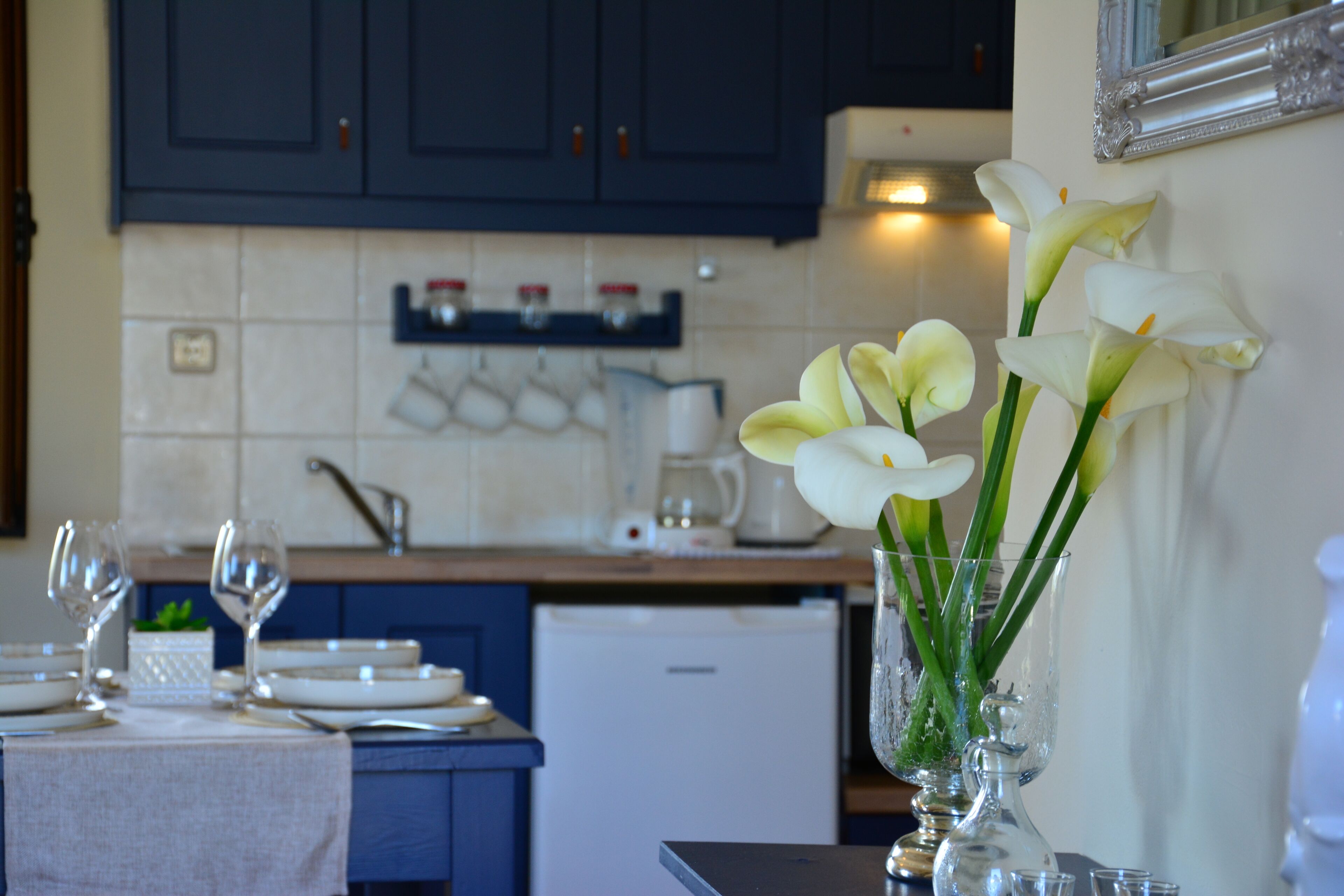 A kitchen with dark cabinets, a tiled backsplash, and a dining area with a table set for two.