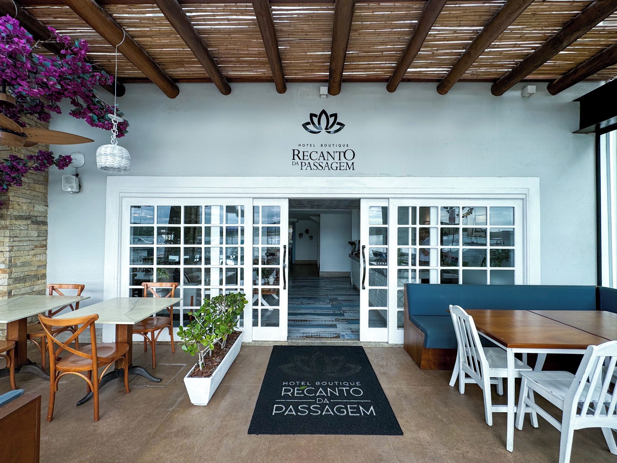 A hotel entrance with a modern design, featuring a reception desk, seating area, and a staircase leading to the interior.