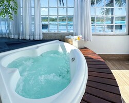 Un jacuzzi con vistas a un cuerpo de agua y colinas.