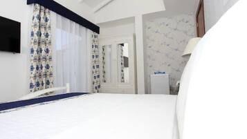 Quarto de hotel com uma cama grande, mesa de cabeceira, espelho e guarda-roupa.