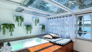 Un área de spa con hidromasaje, asientos de madera y plantas colgantes.