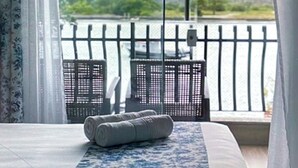 Una habitación con una cama, vistas a un lago y un balcón con barandilla.