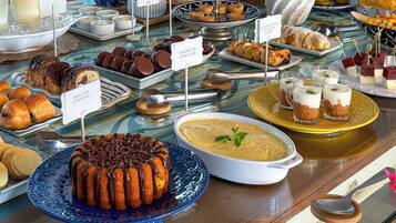 A buffet with various food items including pastries, desserts, and beverages.