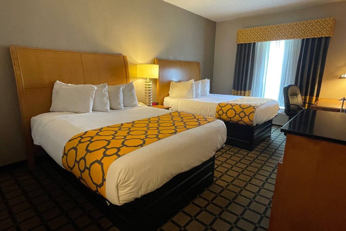 Habitación de hotel con dos camas, un escritorio y una silla.