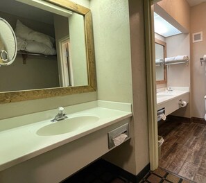 A hotel bathroom with a large mirror, a sink, and a toilet. - Baymont by Wyndham West Plains (West Plains)