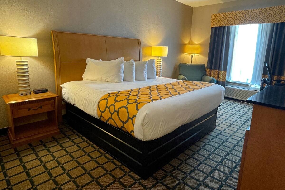 Una habitación de hotel con una cama grande, dos lámparas de noche, un escritorio y una silla.