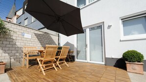 A patio with wooden furniture and a black umbrella. - The Apartment Central (Mainz)