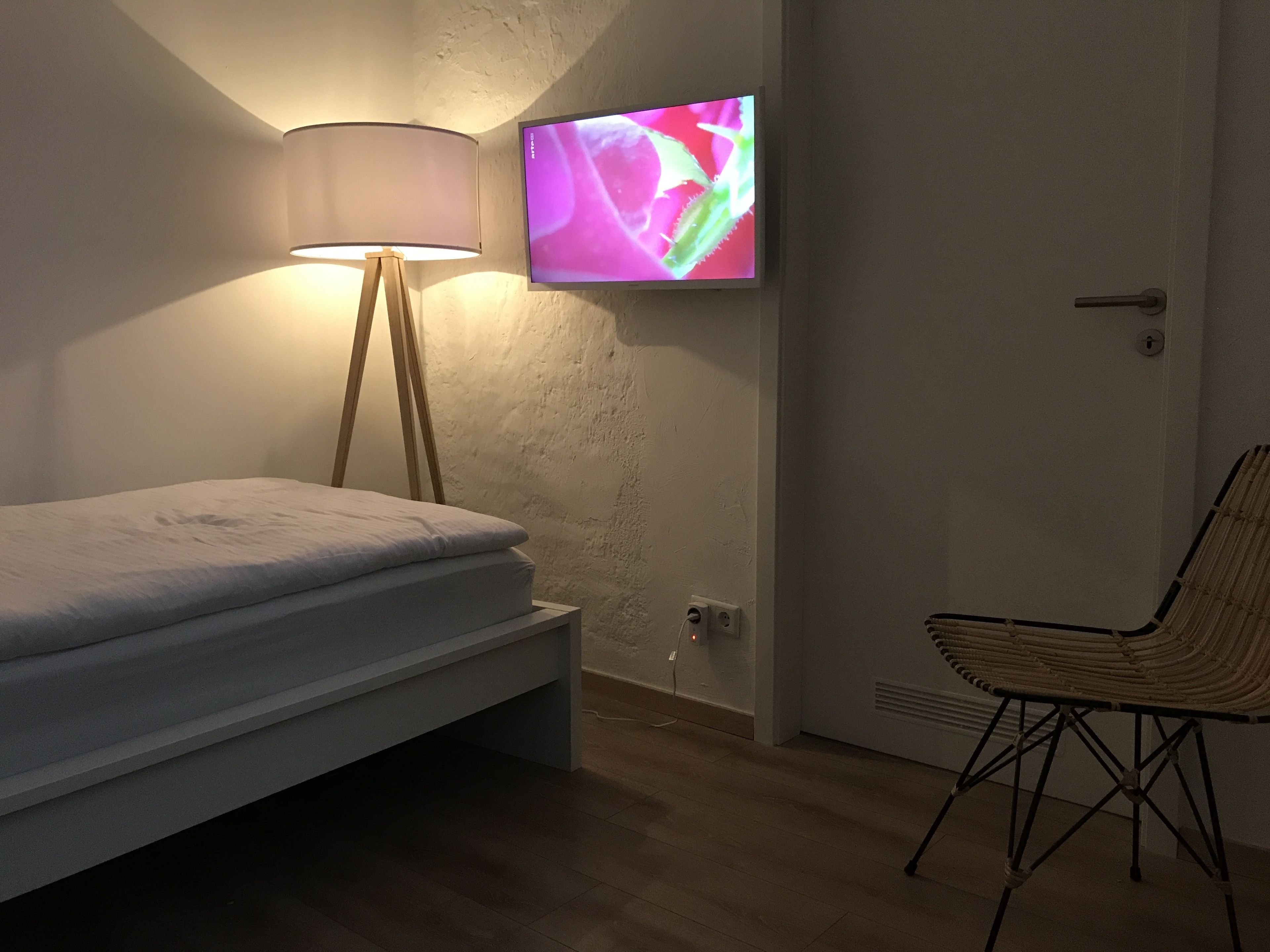 Een slaapkamer met een bed, een lamp, een televisie en een stoel.