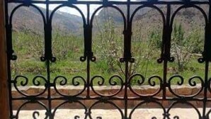 A wrought iron gate with intricate designs, leading to a balcony with a view of a mountainous landscape. - Dar Aya Atlas (Ait Bou Oulli)