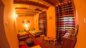 A cozy room with two beds, a small table, a chair, and a decorative bowl on a cabinet. - Dar Aya Atlas (Ait Bou Oulli)