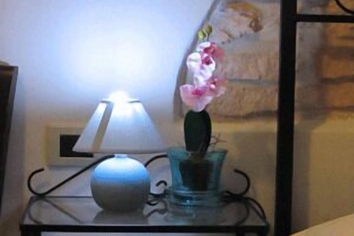 Una mesita de noche con una lámpara y un jarrón de flores.