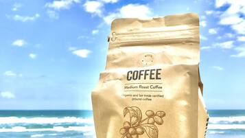 Um saco de café sobre uma superfície de madeira, com uma praia e oceano ao fundo.