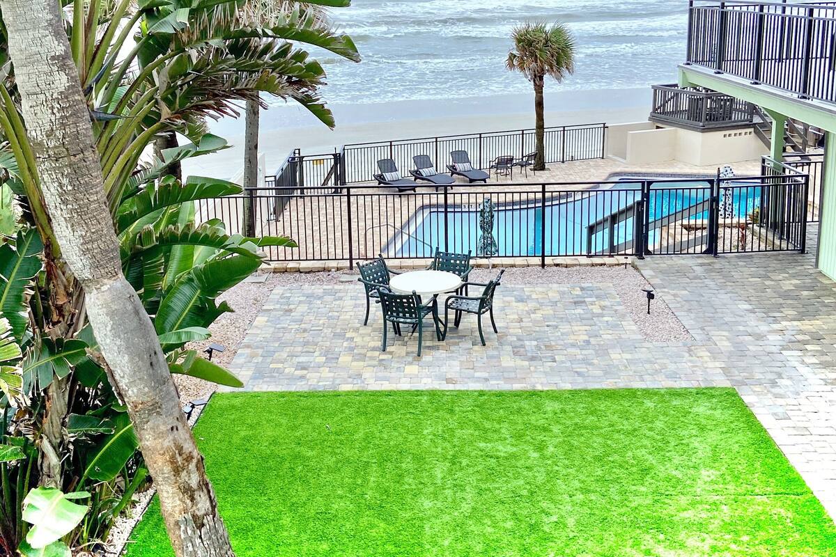 A patio with a pool, outdoor furniture, and a view of the ocean.