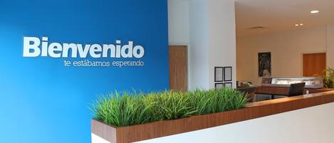 A reception desk with a blue wall and a sign that reads "Bienvenido te estamos esperando".
