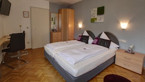 A bedroom with two beds, a desk, a chair, a wardrobe, and a TV. - H41 Inn Freiburg (Gundelfingen)