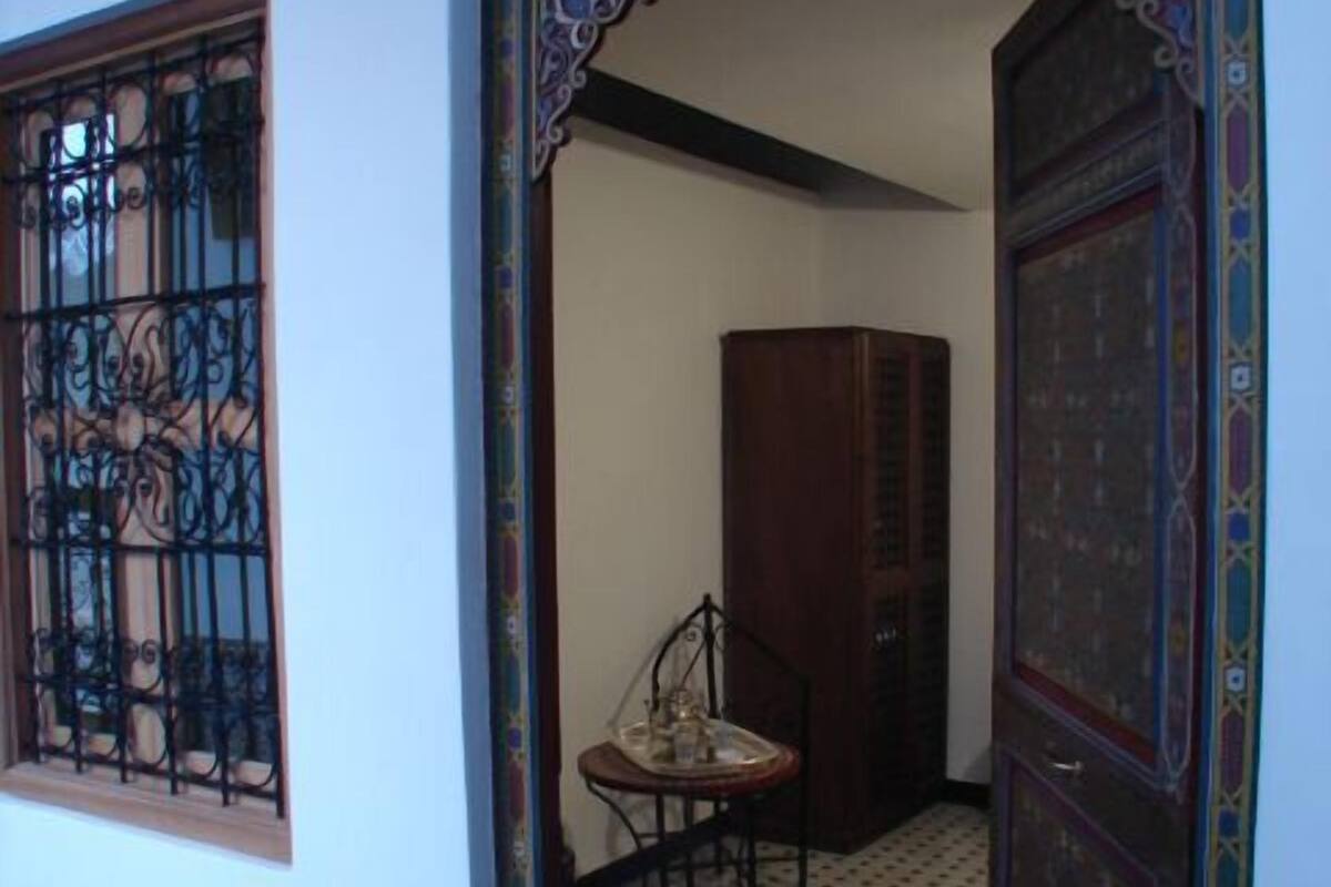 Un corridoio interno con pavimento decorato, una grata su una finestra e un armadietto in legno.