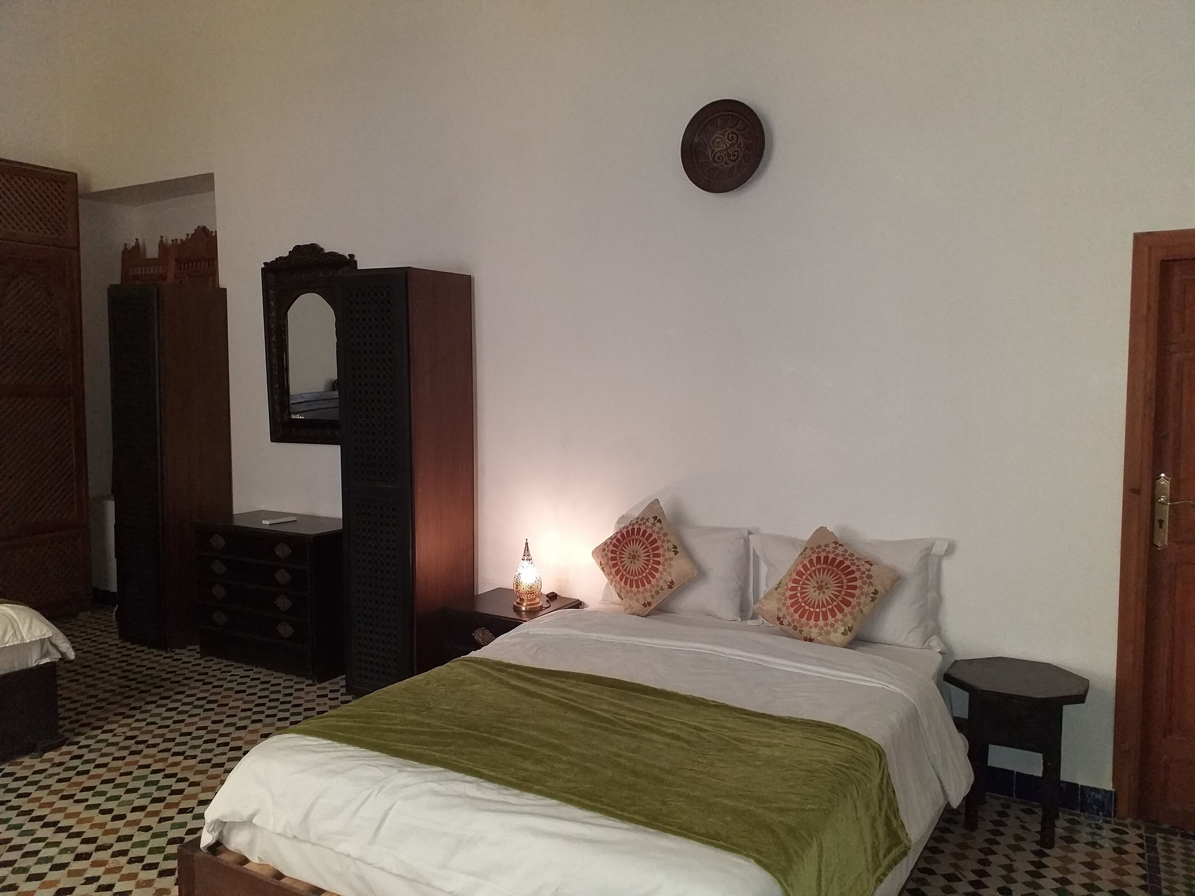 A bedroom with a bed, a nightstand, a dresser, and a mirror.