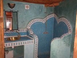 Casa de banho com lavatório, espelho e área de duche.