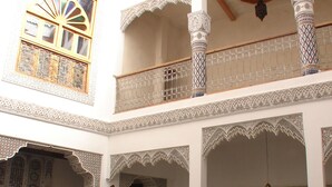 Interior de varios niveles con arcos ornamentales, columnas y suelo de baldosas, que incluye un balcón con vistas.