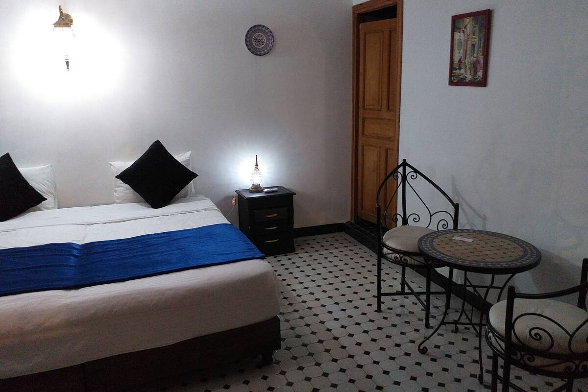Una camera da letto con un letto, un comodino, una sedia e una porta.