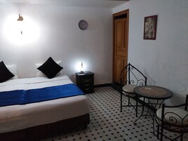 Quarto com cama, mesa de cabeceira, cadeira e porta.