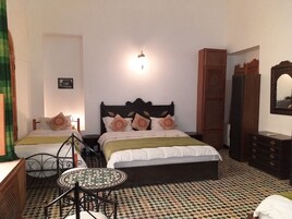 Quarto com duas camas, uma mesinha redonda e um espelho.