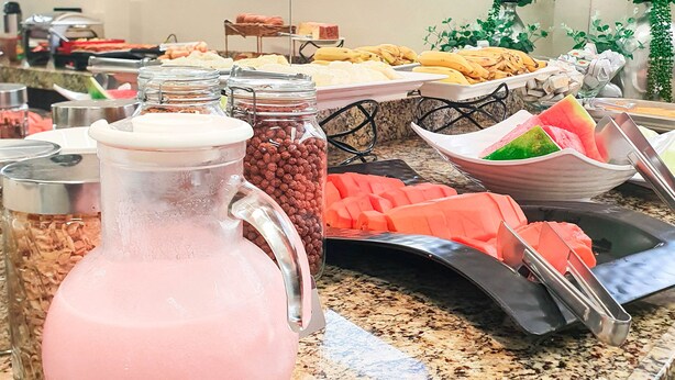 A buffet with various food items and a pitcher of pink beverage labeled 'logurte'. - Avenida Palace Hotel (Joinville)