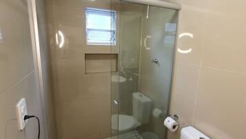 A modern bathroom with a glass-enclosed shower, a toilet, and a sink.