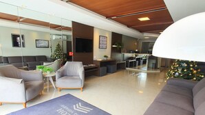 A spacious lobby with a modern design, featuring a large seating area, a reception desk, and a Christmas tree. - Avenida Palace Hotel (Joinville)