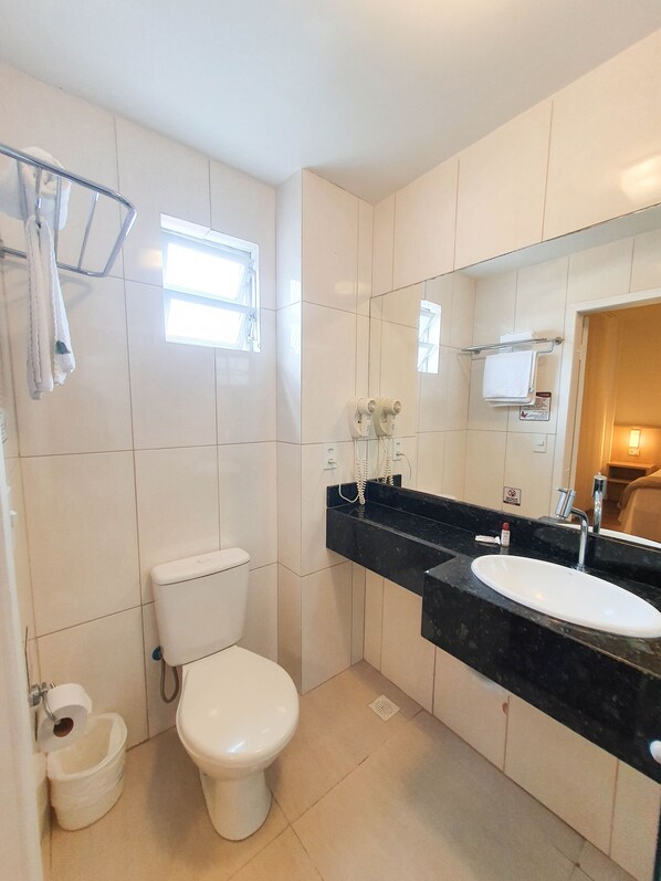 Un baño moderno con inodoro, lavamanos y toallero.