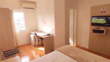 Ein Hotelzimmer mit Bett, Schreibtisch, Stuhl, Fernseher und Fenster.