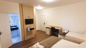 Habitació d'hotel amb dos llits, una taula de treball, televisió i una cuineta petita.