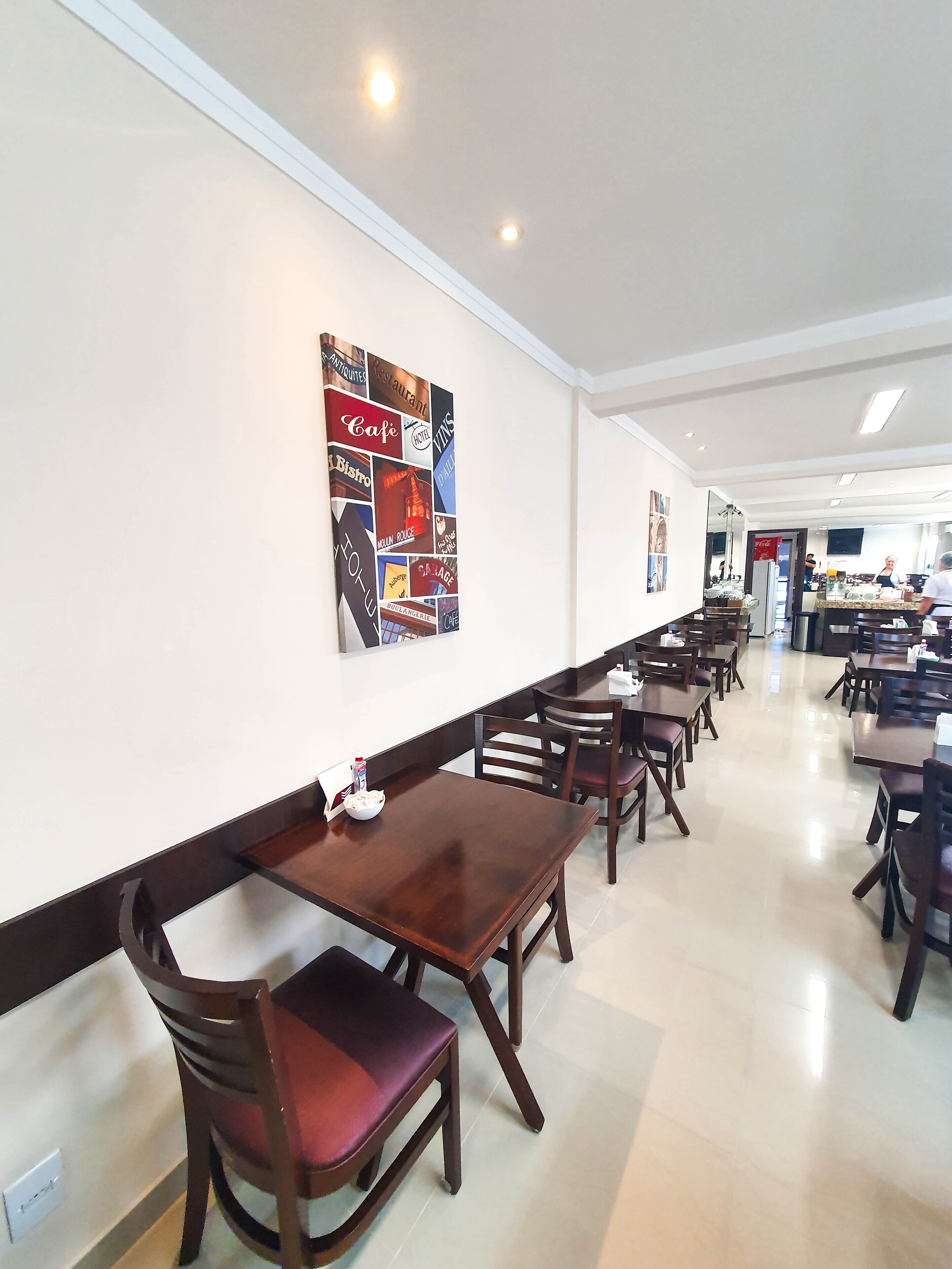 A restaurant with multiple tables and chairs, a wall with a collage of vintage-style signs, and a clean, modern interior.