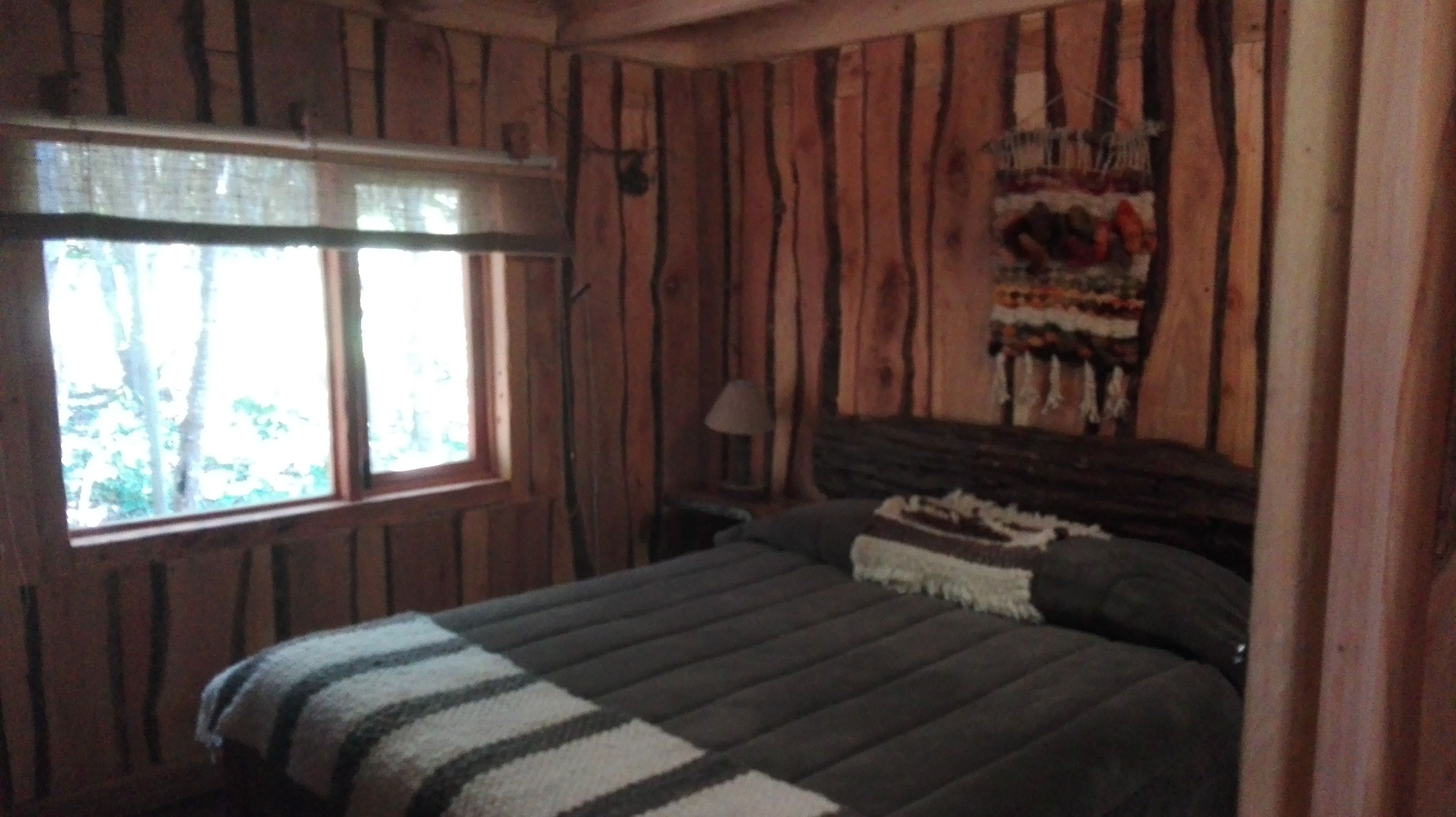 Une chambre à coucher avec un lit, une fenêtre, une lampe et une décoration murale.