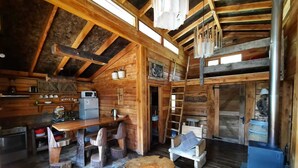 A rustic cabin interior with a wooden interior, a dining area, a kitchen with a microwave, and a wood stove. - Cabañas Rústicas Pucón (Pucón)