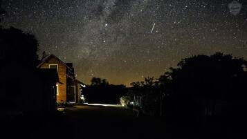 A house with a lit interior, under a starry night sky.