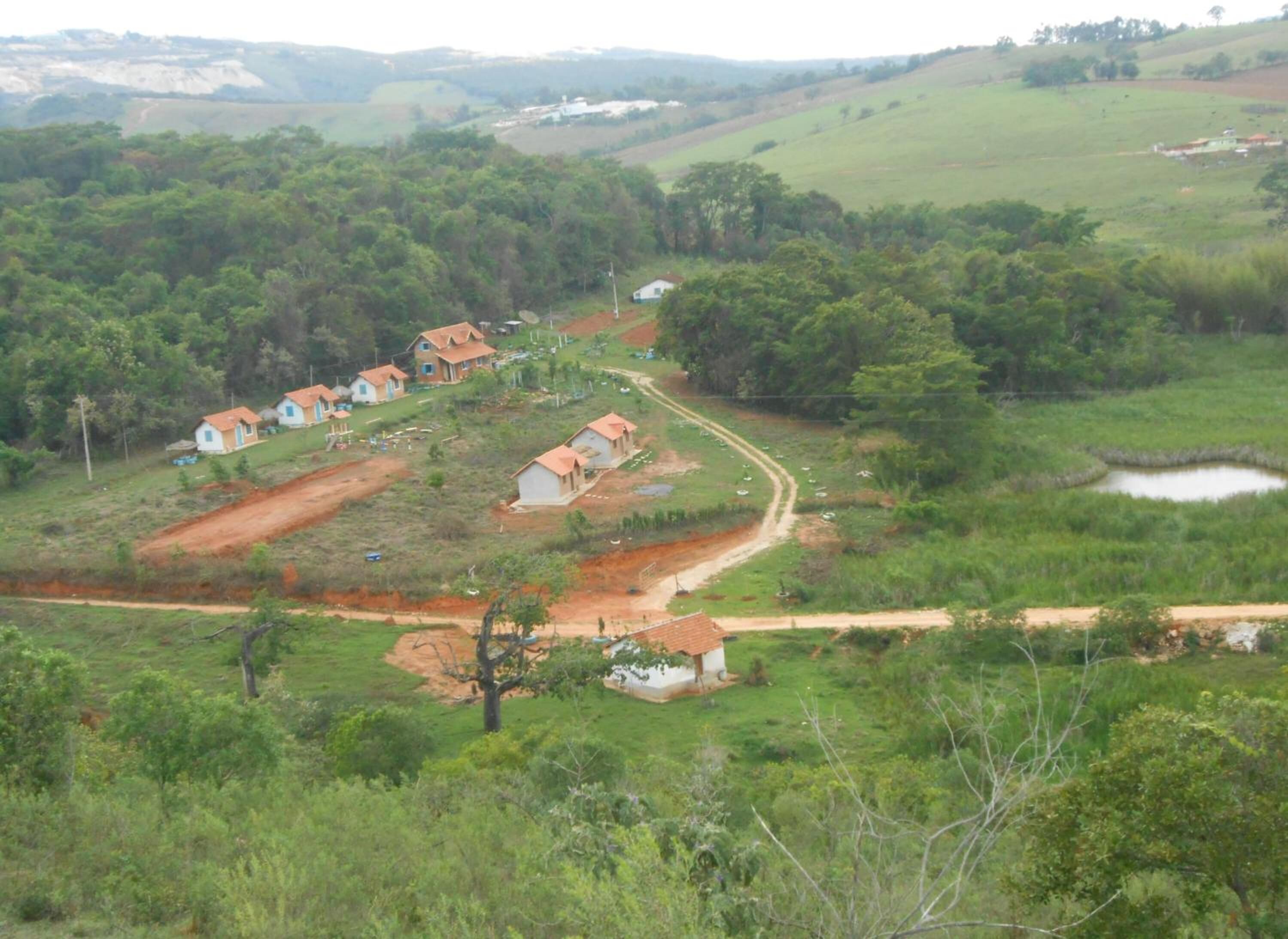 Ländliche Landschaft mit Häusern, einer unbefestigten Straße und einem kleinen Teich.