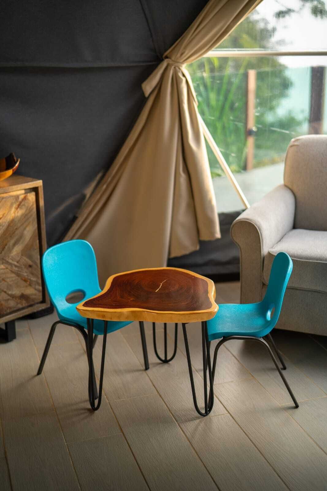 Ett mysigt rum med en soffa, två blå fåtöljer och ett träbord med en unik design.