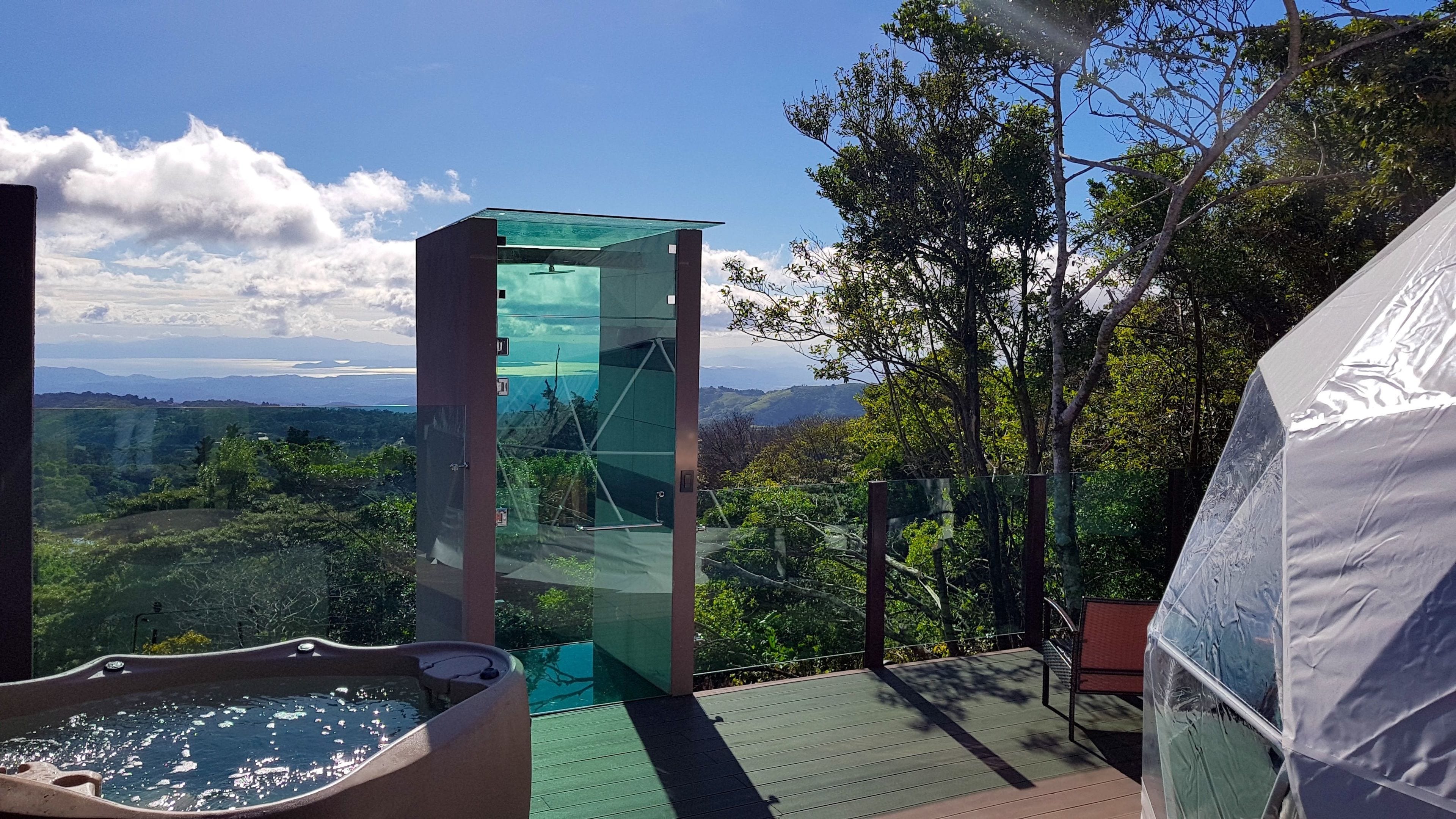 Una estructura con paredes de vidrio, un jacuzzi y vistas a un paisaje montañoso.
