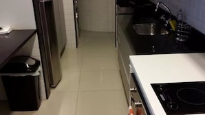 A kitchen with a stainless steel refrigerator, a sink, and a stove. - Etours - Luminoso 3 Quartos Copacabana Souza Lima (Rio de Janeiro)