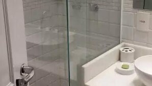 A bathroom with a glass-enclosed shower, a white sink, and a mirror above it. - Etours - Luminoso 3 Quartos Copacabana Souza Lima (Rio de Janeiro)