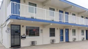 Un motel con fachada azul y blanca, múltiples balcones y unidades de aire acondicionado.