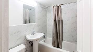 Un baño con un lavamanos blanco, una bañera y una cortina de ducha.