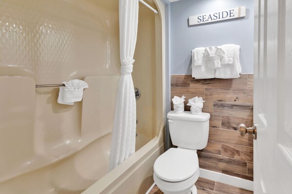 Un baño con bañera, inodoro y cortina de ducha.