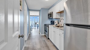Une cuisine moderne avec des meubles blancs, des appareils en acier inoxydable et une vue sur la salle à manger.