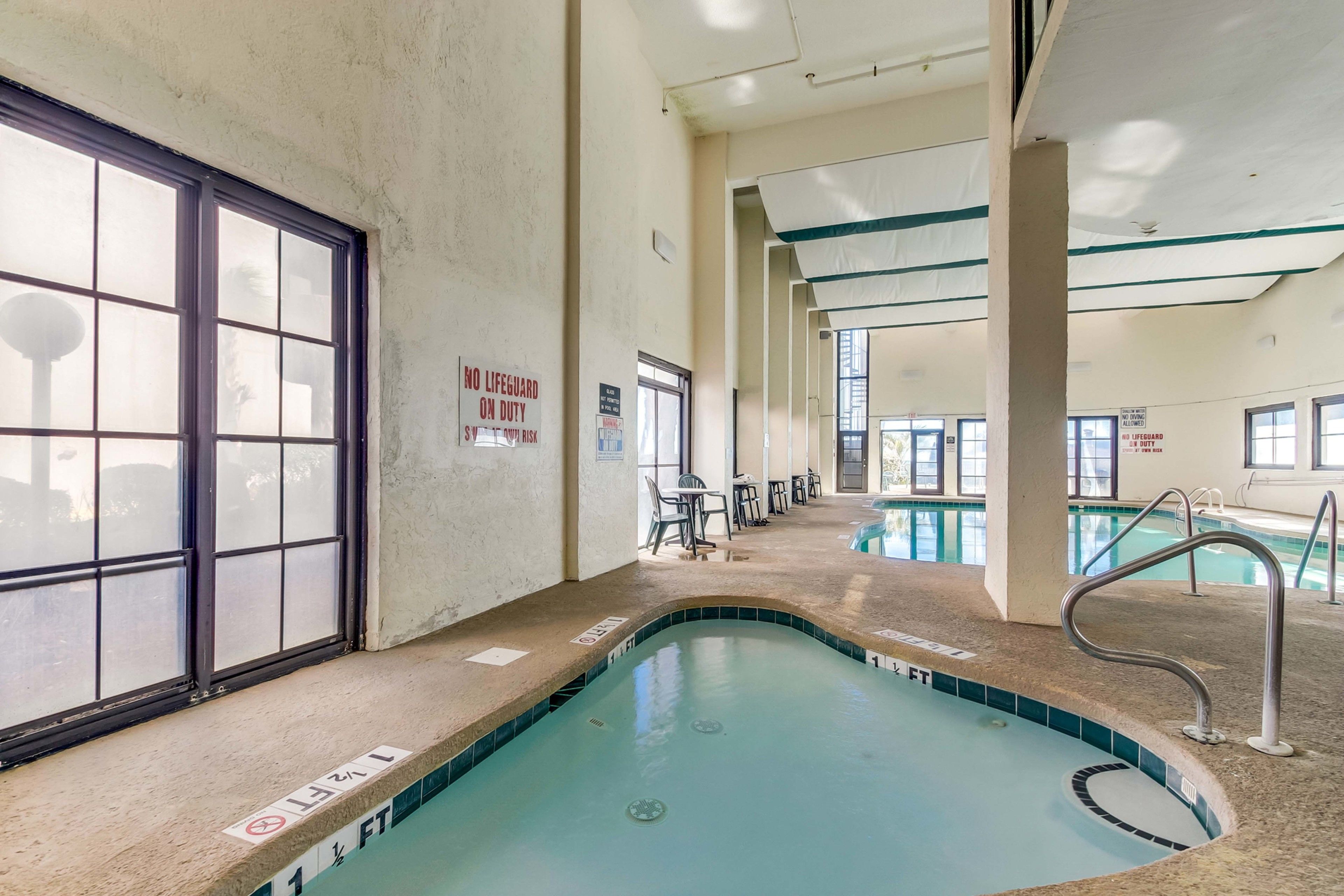 An indoor swimming pool with clear signage, including a 'No Lifeguard on Duty' sign, and a '1 FT' depth marker.