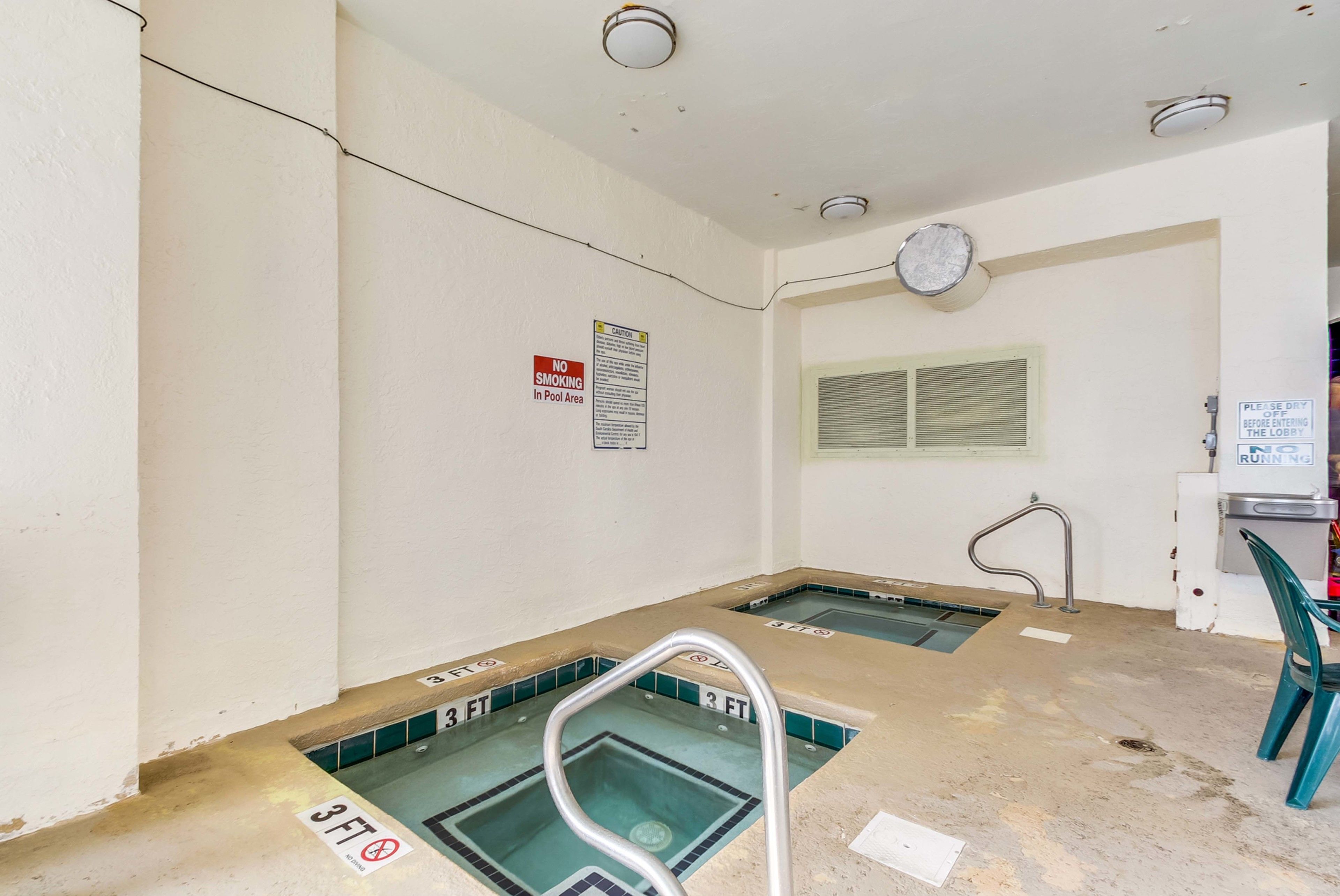 Zona de piscina con carteles de prohibición de fumar, un reloj y un letrero que indica apagar las luces al salir.