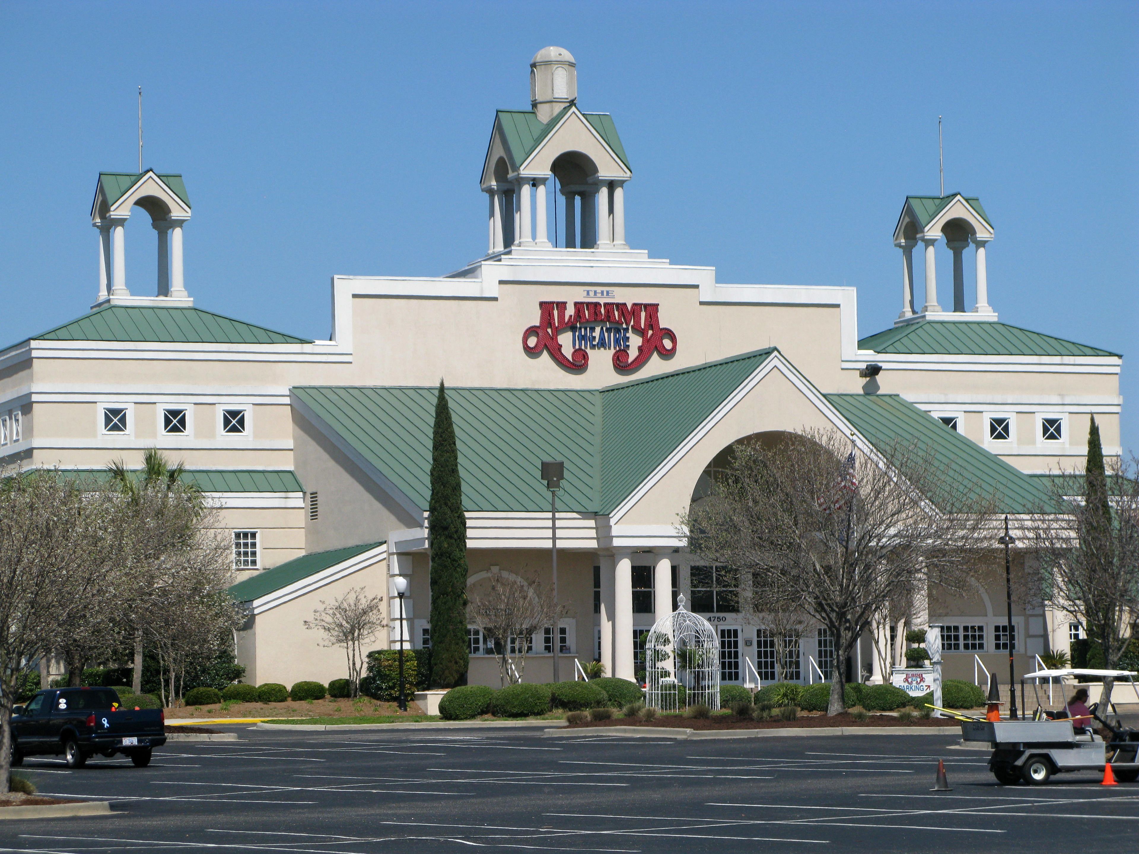 A large building with a green roof and a sign reading "The Alabama Theatre".